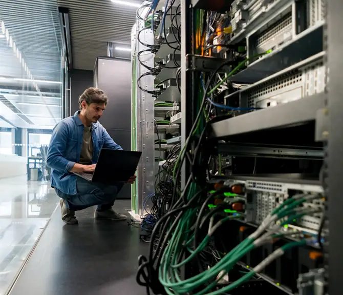Engineer working on server racks with a laptop